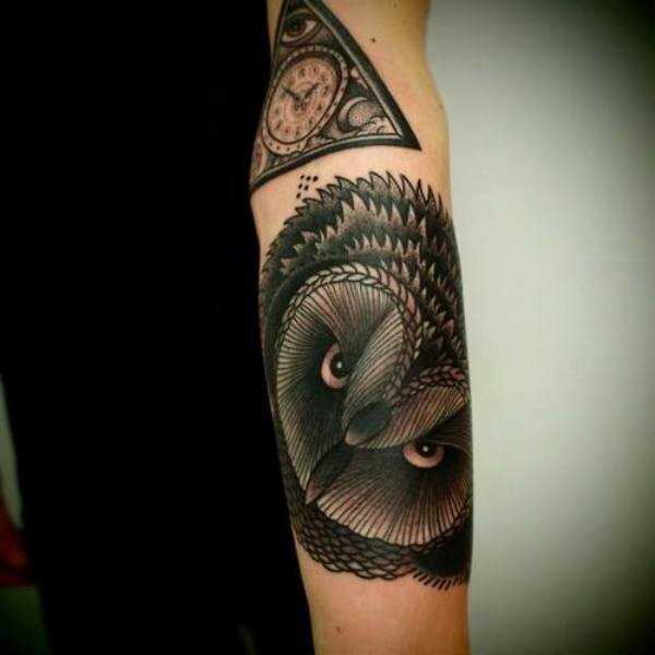 Tatuagem que tem no braço da menina - uma pirâmide com um relógio e uma coruja