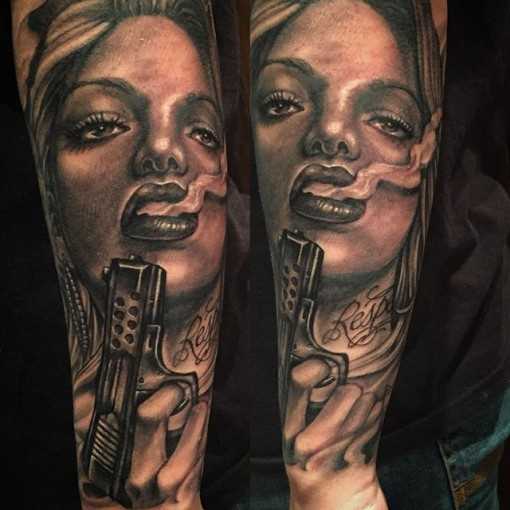 Um submundo de uma tatuagem em estilo chicano no antebraço cara - uma menina com uma arma