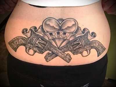 Um submundo tattoo no estilo chicano no cóccix meninas - revólveres e coração