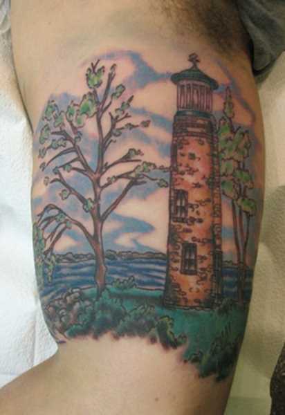 Uma bela tatuagem no braço de um cara - um farol na margem do mar e as árvores