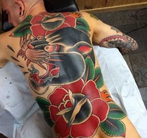 Uma grande tatuagem nas costas do cara - pantera e rosas