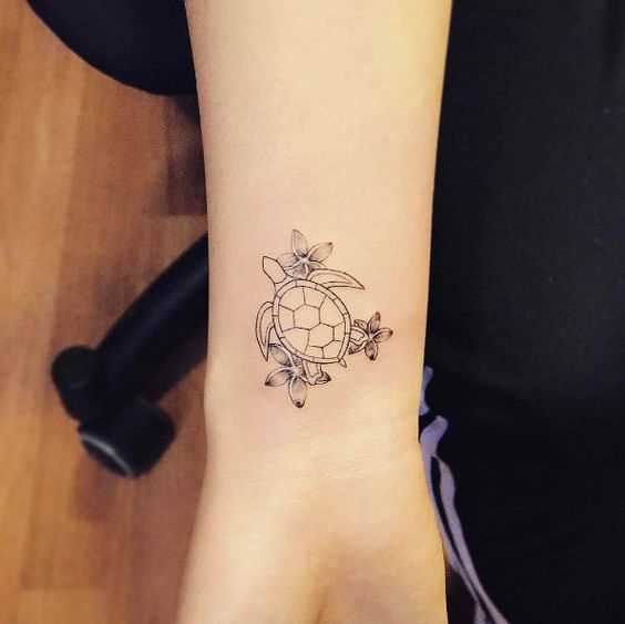 Uma pequena tatuagem de uma tartaruga, com flores no pulso da menina