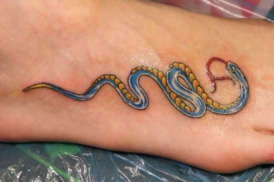 Uma tatuagem em forma de serpente na planta do pé da menina