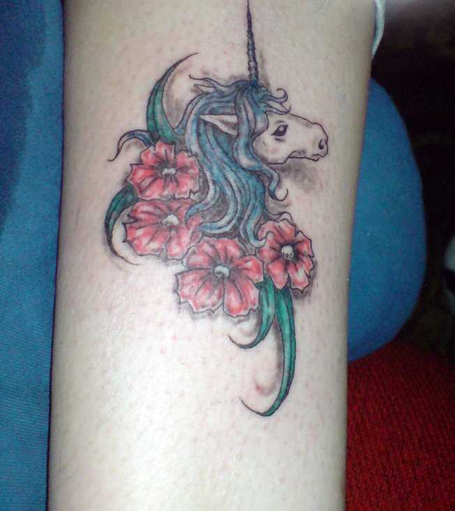 Uma tatuagem em forma de unicórnio e e flores no ombro da menina