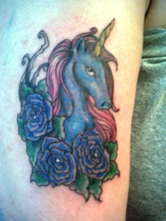 Uma tatuagem em forma de unicórnio, e rosas no ombro da menina