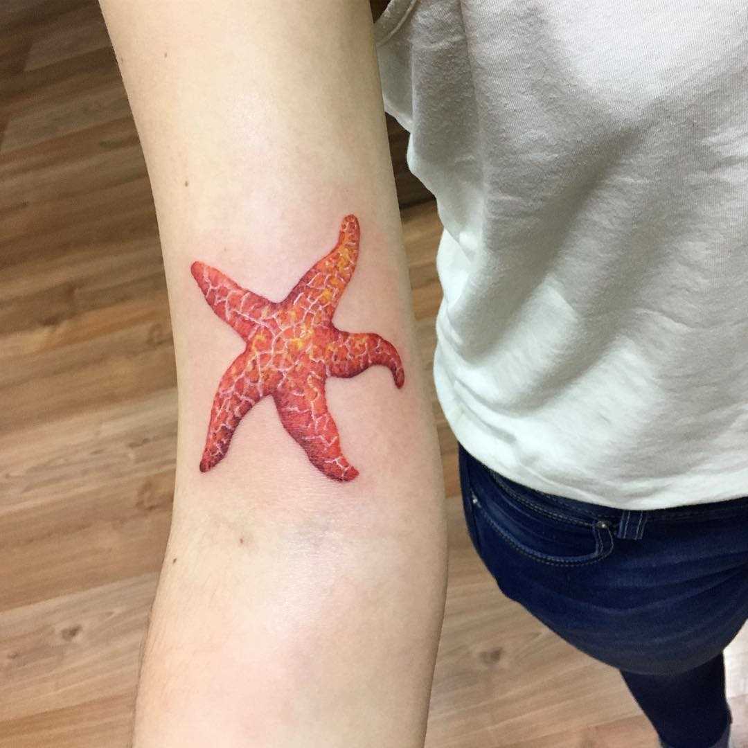 Vermelho tatuagem de estrela na mão da menina